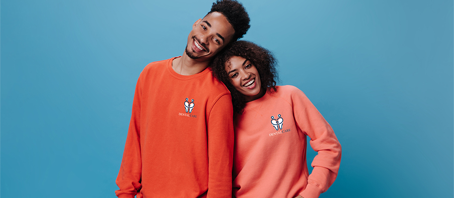 Two people wearing red and coral sweatshirts on a blue background 