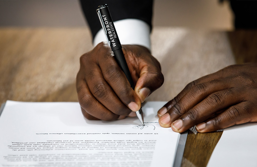 man signing paper with pen